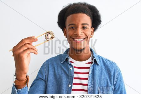 Young african american man eating sushi using chopsticks over isolated white background with a happy face standing and smiling with a confident smile showing teeth