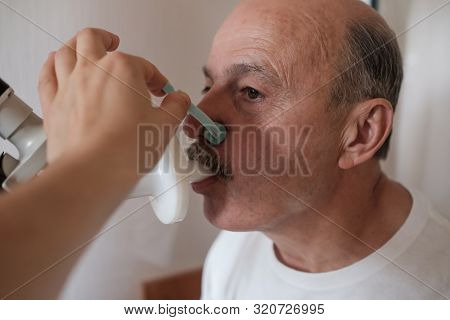 Senior Hispanic Man Man Testing Breathing Function By Spirometry