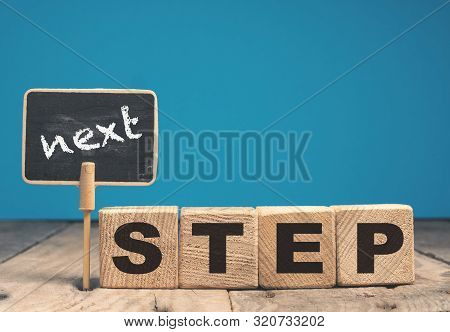 Wooden Blocks And A Chalkboard With The Words Next Step, Motivation Or Career Concept