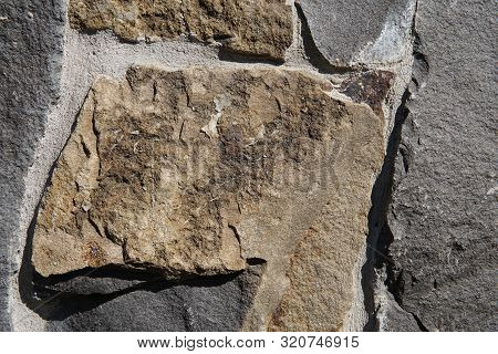 Decorative Wall Of Artificial Torn Stone In Brown Tones. Stone Masonry In Geometric Pattern As Backg