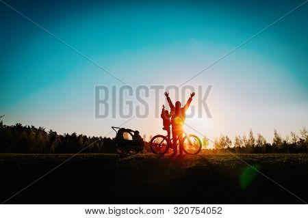 Happy Father And Little Daughters Riding Bike At Sunset