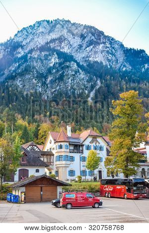Schwangau, Germany - Oktober 09, 2018: Beautiful European House And Parking On Background Of High Mo