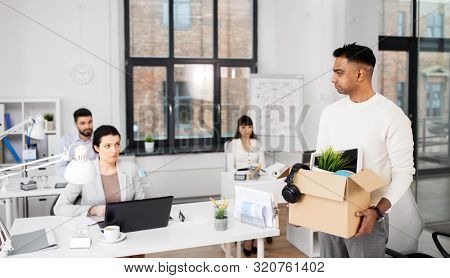 business, firing and job loss concept - sad fired indian male office worker with box of his personal stuff