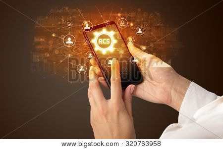 Female hand holding smartphone with RCS abbreviation, modern technology concept