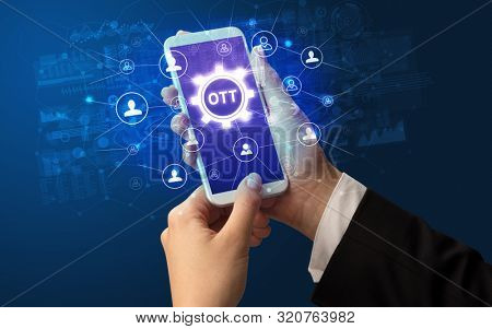 Female hand holding smartphone with OTT abbreviation, modern technology concept