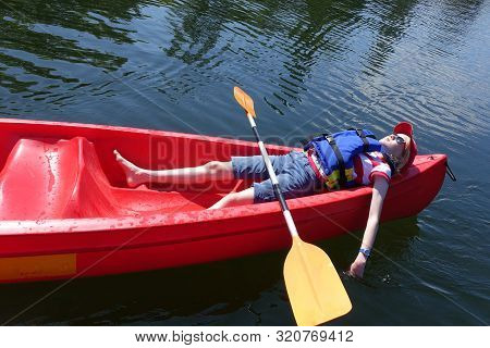 Worn Out, Child Lying Down In Canoe On A Hot Summers Day;