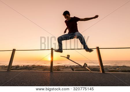 Skater Make Trick Kickflip Against The Beautiful Orange Sunset.