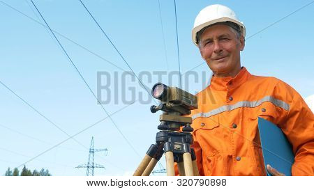 Experienced Surveyor Stands Near Dumpy Level Holding Folder