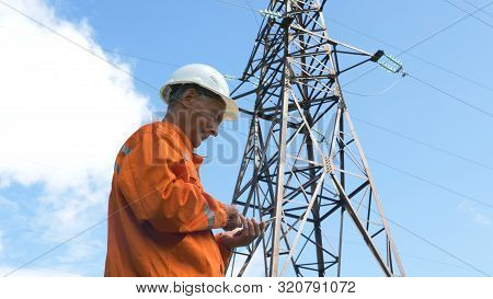 Aged Survey Specialist Types On Smartphone Under Power Lines