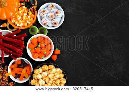 Halloween Candy Side Border Over A Black Stone Background With Copy Space. Assortment Of Sweet, Spoo