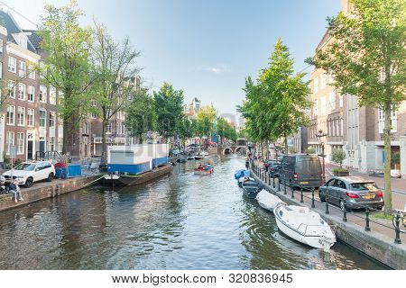 Amsterdam, Netherlands - June 6, 2019: Canal With Boats In Summer Day.