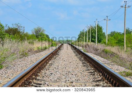 Railway Tracks Stretching Into The Distance In The Middle Of A Green Forest