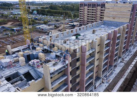 Construction Of A Multi-storey Building. Workers Lay Out A Wall Of Brick. The View From The Top.