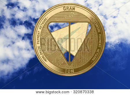 Gold Coin Cryptocurrency Gram, Ton, Round Against The Sky With Clouds.