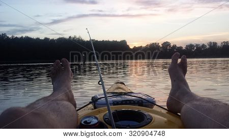 Reclining In A Kayak At Sunset With Feet Up With An Ice Cold Beverage And Fishing Gear