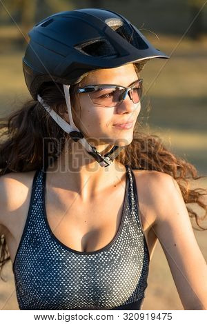 Girl On A Mountain Bike On Offroad, Beautiful Portrait Of A Cyclist At Sunset, Fitness Girl Rides A 