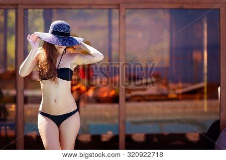 Girl In A Black Bathing Suit And Half-covered Hat Field Face Closeup On The Background Of Tinted Gla
