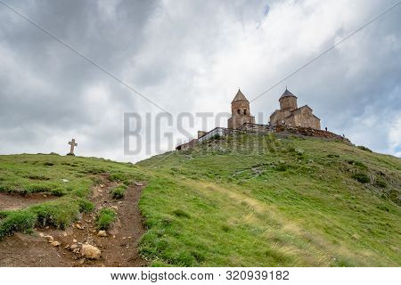 Gergeti Trinity Church Or Tsminda Sameba, Dramatic Landscaoe With Clouds. Gergeti Church Stands Near