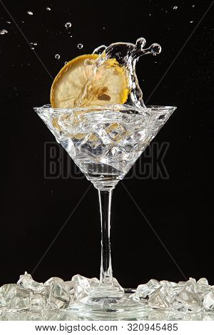 Glass Of Water, Lemon And Watersplashes On A Black Studio Background