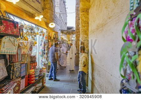 Doha Qatar - July 11 2019; Focus On Arabic Man In Customary White Robes In Lane Among Market Vendors