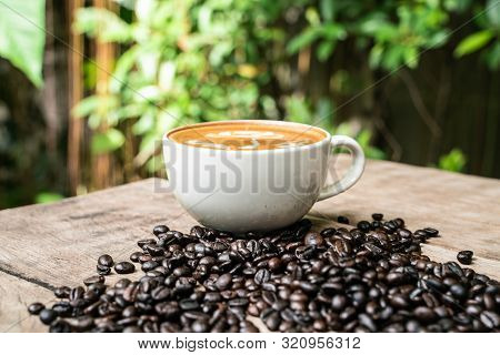 Latte Art Coffee Cup With Coffee Bean On Wood Table