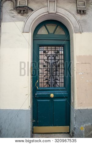 Paris / France - 06 26 2019: Arch Door With Semicircular Top And Door Window Protected By Ornate Met