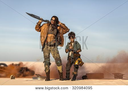 Post Apocalyptic Woman And Boy With Weapons Outdoors. Broken Burning Motorcycle And Dead Wasteland O