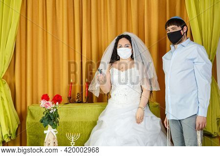 During The Chupa Ceremony In The Synagogue, The Bride And Groom Stand Next To The Bride Holding A Gl