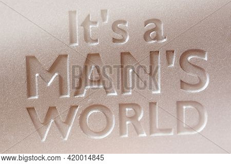 Close-up Inscription Its A Mans World Debossed On A Metal Plate.