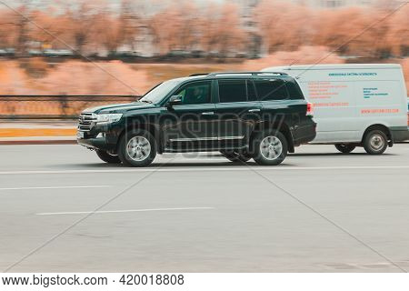 Black Suv Car Toyota Land Cruiser 200 At The City Driveway. Auto Moving At High Speed On The Street.