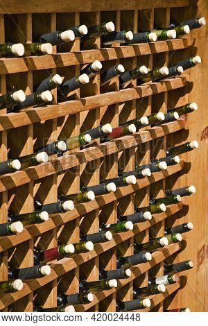Opened Wine Bottles Stacked In Wooden Racks In Restaraunt. Lots Of Corked Bottles. Pour Wine To Orde