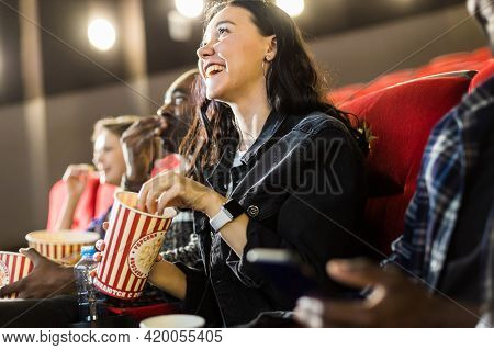 Friends Are Watching A Movie In The Cinema With Popcorn. People Sit In The Armchairs Of The Cinema A