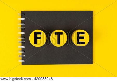 Business And Finance Concept. On A Yellow Background Lies A Black Notebook, Yellow Wooden Circles Wi
