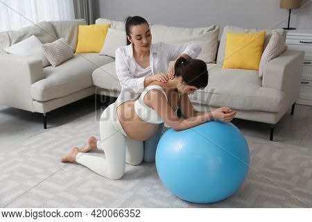 Doula Working With Pregnant Woman In Living Room. Preparation For Child Birth