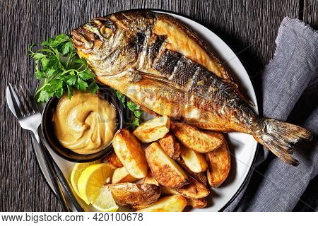 Grilled Sea Bream, Orata, Dorado Fish Served On A Plate With Roasted Potatoes And Mustard, Horizonta