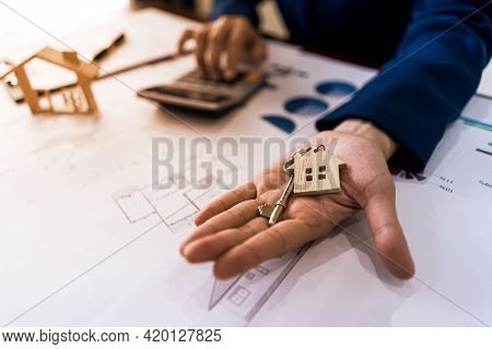 Realtor Real Estate Or Home Seller Showing Key House And Calculatate Price Of Housing. Offer Of Purc