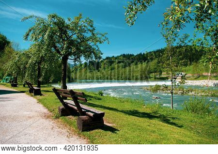 Wooden Bench On The River Bank In Mozirskij Gaj Park Slovenia.