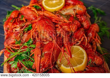Boiled Crayfish On A Black Background With Herbs And Lemon Juice. Boiled Delicious Crayfish