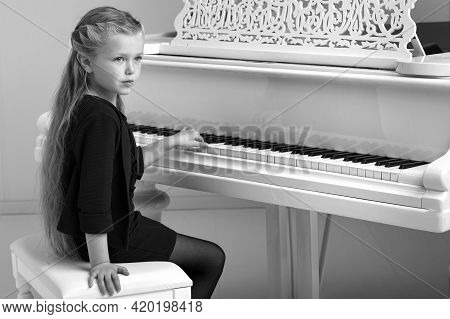 Beautiful Little Girl Playing On White Grand Piano