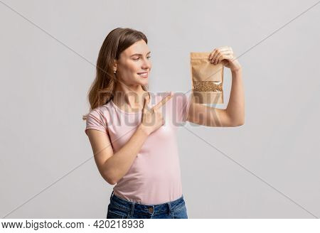 Young Woman Pointing At Brown Kraft Paper Doypack Bag With Granola