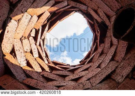 A Look Up From A Primitive Drainage Well. The Walls Are Made Of Rough Plain Bricks And There Is A Dr