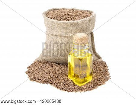 Cumin Essential Oil. Glass Bottle Of Cummin Oil. Caraway In A Sack Of Isolated On A White Background