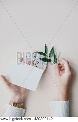 Woman holding a blank card with Ruscus leaves