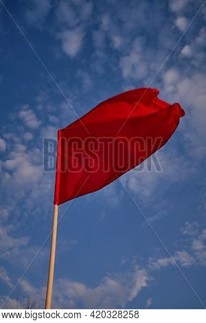 Red Flag With Blue Sky With Clouds, Strong Wind Flying Red Flag. Red Flag Warning Flags
