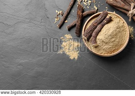Powder In Bowl And Dried Sticks Of Liquorice Root On Black Table, Flat Lay. Space For Text