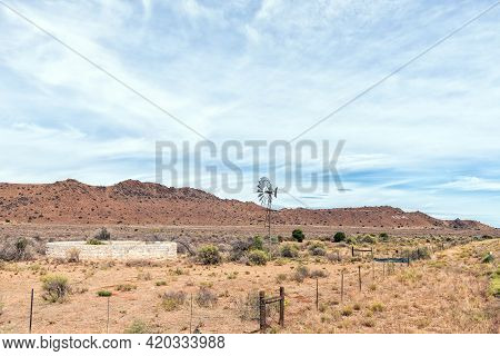 A Windmill And Dam Next To Road N1 Between Richmond And Three Sisters In The Northern Cape Karoo. A 