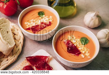 Two Bowls Of Salmorejo Tomato Soup With Jam, Olive Oil And Boiled Egg On Marble Table. Spanish Cold 