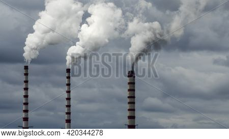 Industrial Smoke From Chimney On Dramatic Sky Background. View Of High Chimney Pipes With Grey Smoke