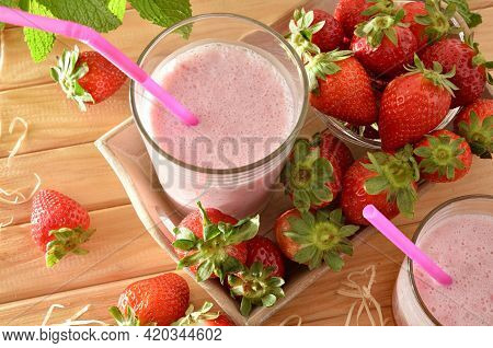 Strawberry Smoothie With Milk In Glass Containers On Wooden Table With Tray Full Of Strawberries In 