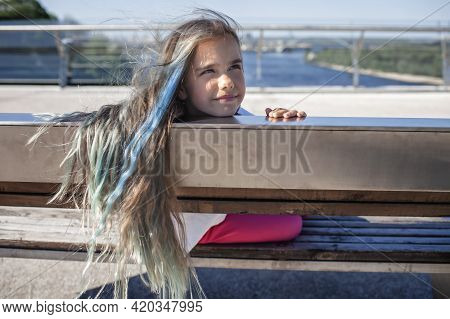 Brunette Preteen Girl With Blue Color Highlights Sitting On The Bench On The Bridge And Looking At R